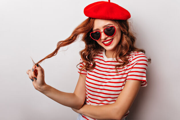 快乐兴高采烈的红发女孩在玩她的卷发一个戴贝雷帽的迷人女人法国表情休闲