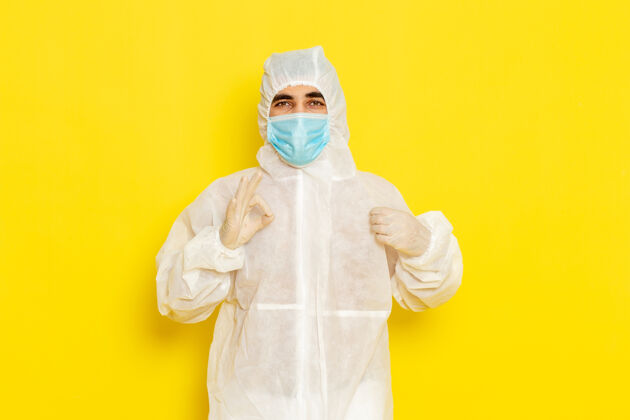 服装身着特殊防护服 戴着面具的男性科学工作者的正面图 摆在淡黄色的墙上科学医学防护