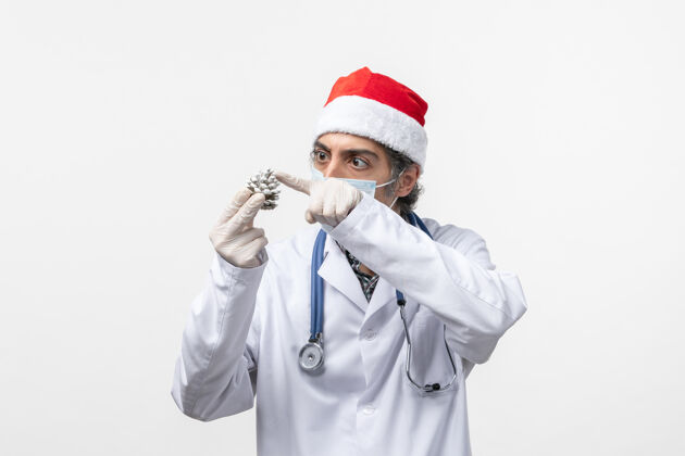 制服正面图男性医生拿着白色地板上的圆锥体-圣诞健康病毒圣诞节专家护士
