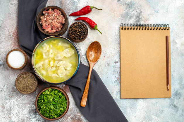 香料俯视图杜什巴拉黑色桌布碗肉不同香料绿色木勺笔记本裸体表面勺子顶部午餐
