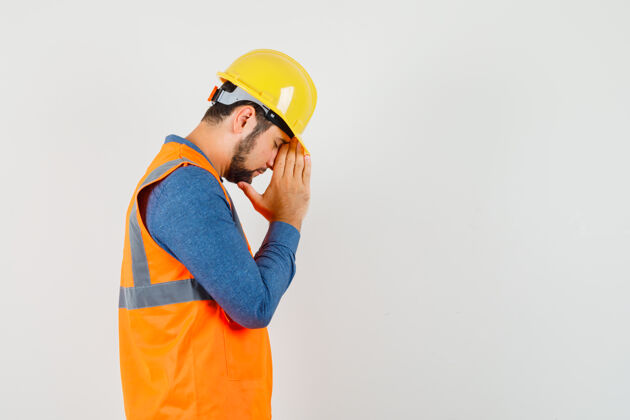 安全帽穿着衬衫的年轻建筑工人手牵手祈祷工厂设备职业