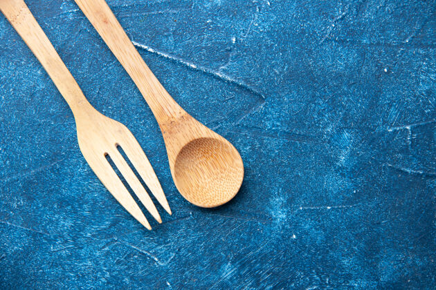 木头勺子顶视图木制叉子勺子放在蓝色桌子上自由活动烹饪地方饭