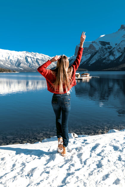 运动一个人在户外玩 享受完美的自然景观蓝天 大山 湖泊冬天寒冷的天气温暖的针织红毛衣和紧身牛仔裤长发天空冷