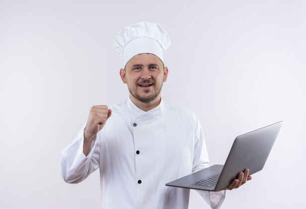 年轻身着厨师制服的年轻帅哥面带微笑 手持笔记本电脑 在与世隔绝的空白处举起拳头微笑厨师提高