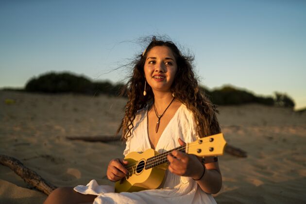 娱乐浅浅的焦点拍摄一个微笑的女性在海滩上玩黄色的四弦琴乐器音乐家手