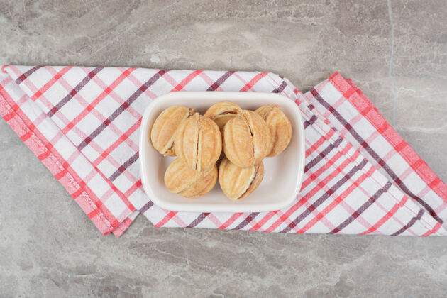 焦糖在桌布上放一碗核桃形状的饼干饼干面包房桌布