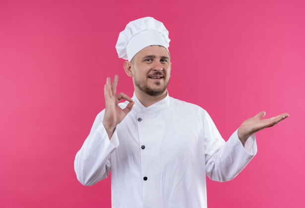 厨师面带微笑的年轻帅哥厨师身着厨师制服 做着“ok”的手势 在粉色的空间里露出一只孤立的空手做好厨师