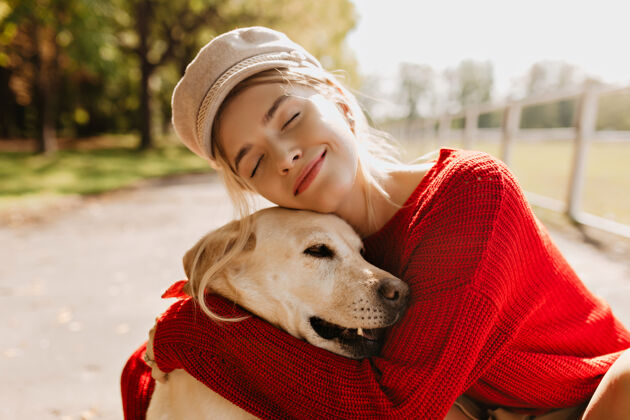 狗美丽的金发女郎和她心爱的狗在秋天一起在户外度过一个美丽的女人和她的宠物在公园里的美丽肖像哺乳动物小猎犬多彩