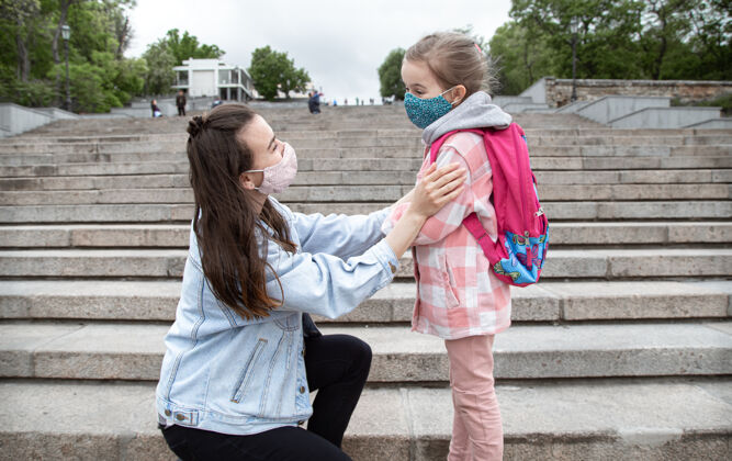 脸妈妈带着她的小女儿 一个女学生 踏上了上学的路冠状病毒大流行的教育理念冠状病毒新正常面具