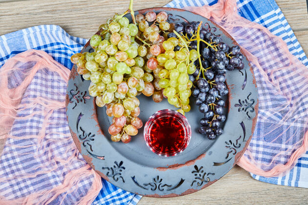 果汁一束葡萄和一杯果汁放在陶瓷盘子里 还有桌布绿色顶饮料