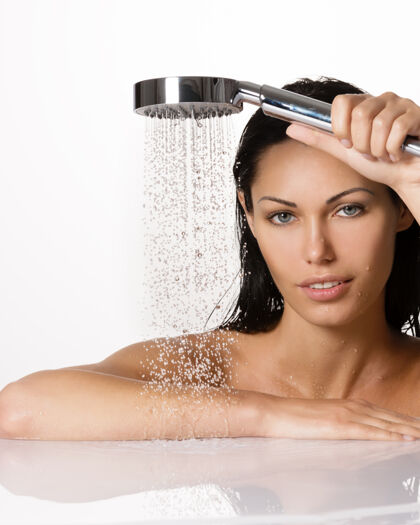 放松一个漂亮的黑发女人的肖像拿着淋浴在手与下降的水黑发皮肤滴