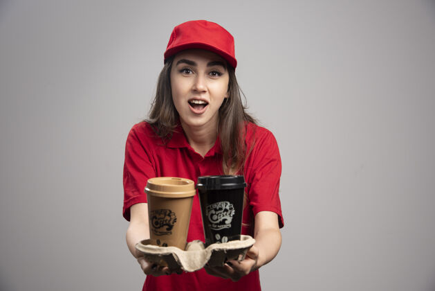 员工穿着红制服送咖啡的漂亮女送货员咖啡快递工人