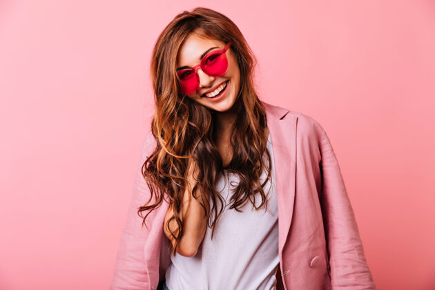 可爱戴着粉色眼镜的姜黄色迷人女孩 表达着积极的情绪快乐的年轻女子喜欢拍照放松享受模特