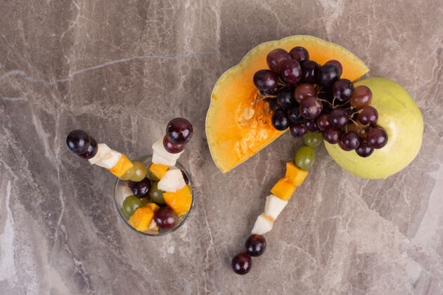 玻璃大理石表面有水果棒和新鲜水果葡萄切割南瓜