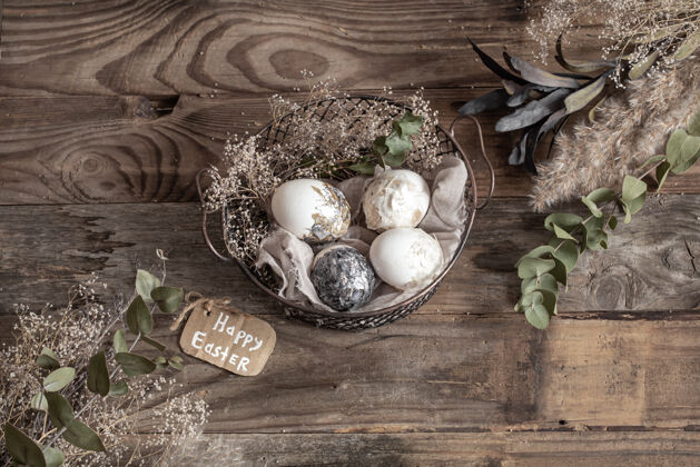 心愿复活节彩蛋放在装饰篮子里 木桌上放着干花复活节快乐顶部节日干花