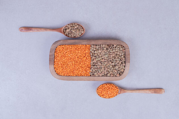 谷物两种生豆子和小扁豆放在带勺子的木盘里视图扁豆天然