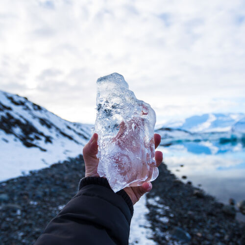 冰岛特写一个人拿着冰在冰岛与模糊的背景冰冻冰岛雪