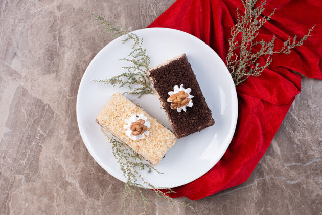 块白盘子上放两片蛋糕 用红桌布包着甜点切片顶部视图