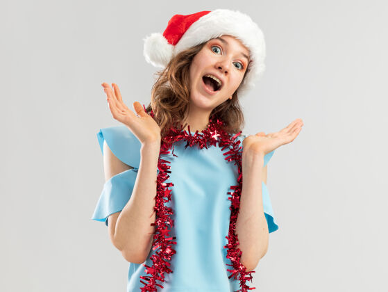 快乐穿着蓝色上衣 戴着圣诞老人帽子 脖子上戴着金属丝的年轻女子 看起来疯狂 快乐 兴奋 尖叫快乐圣诞老人新年