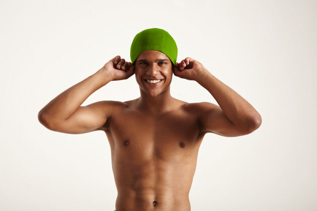 比赛快乐微笑的非洲裔美国游泳运动员戴上他的绿色泳帽看着白色游泳池健身奥运会