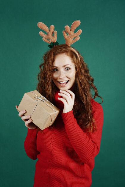 女人兴奋的女人打开圣诞礼物的画像举行毛衣礼物