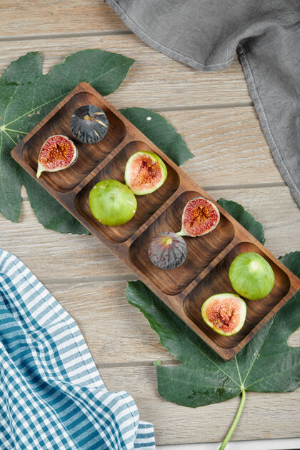 营养用一片叶子和一块桌布放在木盘上 放上一整片成熟的绿色和黑色无花果无花果美味水果
