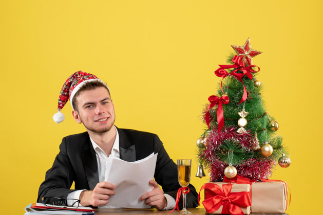 圣诞节正面图男性工人坐在他工作的地方后面拿着黄色的文件颜色男工人商人