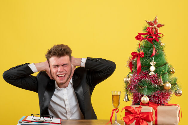 圣诞节正面图：坐在工作场所后面的男工人 耳朵贴着一张黄色的照片主管坐关门