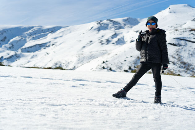 冷快乐的高加索男孩冬天穿着暖和的衣服在雪山上霜孩子雪