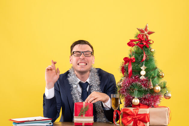 快乐的男人正面图：圣诞树旁的餐桌旁 喜人吉祥标志 黄色礼物圣诞黄色婚礼