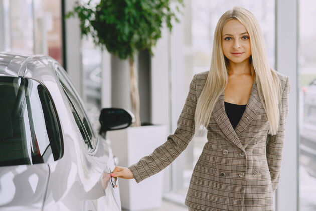 人汽车沙龙里的女士买车的女士穿着棕色西装的优雅女士经销商成人女人