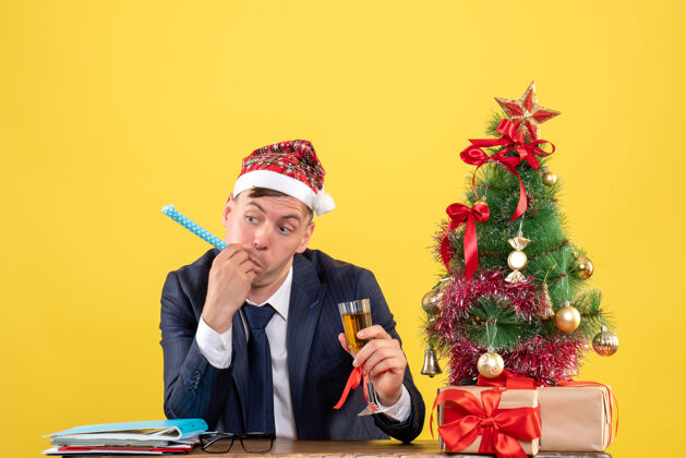 礼物前视图的商人使用喧闹胡尔丁香槟坐在圣诞树附近的桌子上 并提出了黄色桌子帅哥成人