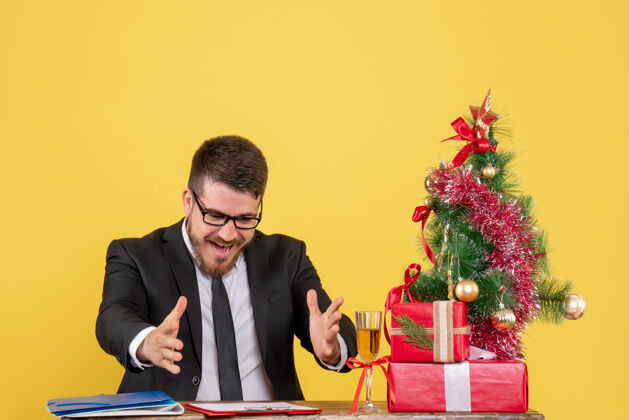 工人正面图：一位男性工人在他的桌子后面 黄色的圣诞树上放着礼物和圣诞树工作年份颜色