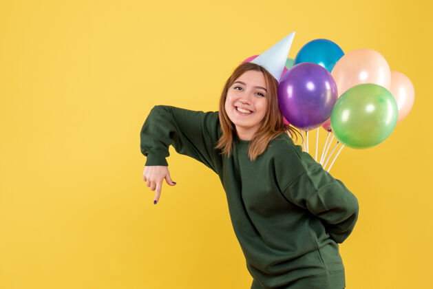 年正面图年轻女性藏着五颜六色的气球磁盘人年轻的女性