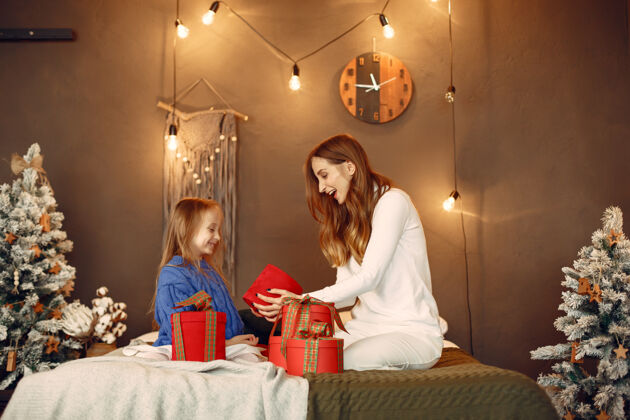 圣诞节人们在为圣诞节做准备母亲在和女儿玩耍一家人在节日的房间里休息孩子穿着蓝色毛衣装饰庆祝闪亮