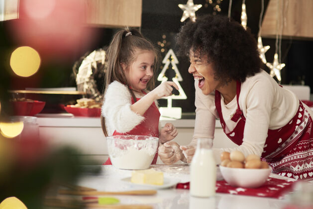 生活妈妈和女儿在厨房里过圣诞节面粉嬉戏后代