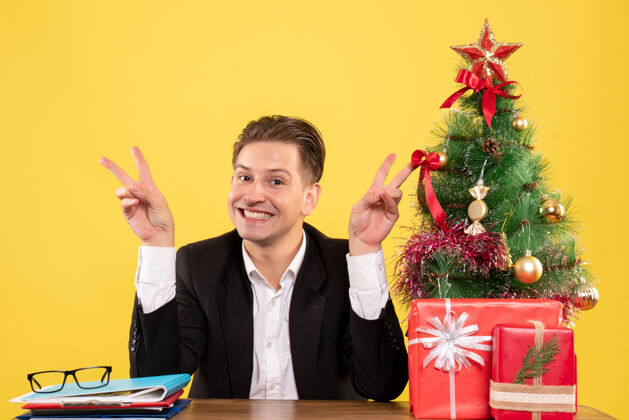 男正面图身着西装的男工人坐在工作台后面微笑着圣诞节行政人员坐着