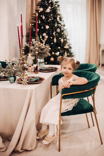 可爱漂亮的白人女孩穿着漂亮的裙子在圣诞树旁的厨房里微笑着传统模型快乐