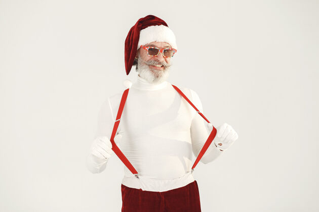 眼镜时髦的灰色头发的圣诞老人男人穿针织衣服爷爷戴着圣诞老人的帽子事件帽子胡须