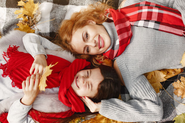 可爱时髦的母亲带着女儿黄色的秋天戴着红领巾的女人女性年轻快乐