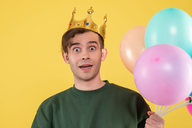 喜悦正面图：戴着皇冠的年轻人拿着黄色的气球人颜色幸福