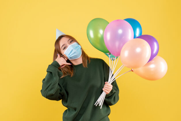 庆祝正面图：手持彩色气球的年轻女性病毒人流行性疾病