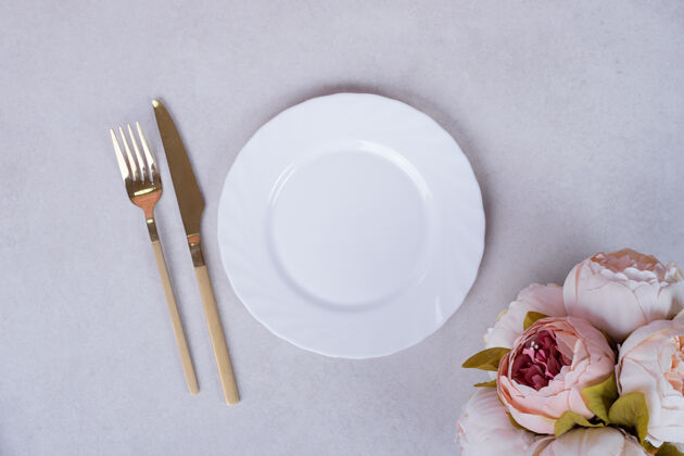 礼物牡丹玫瑰 餐具和盘子放在白色的表面上风景顶视图花