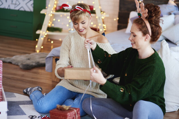 友谊两个女孩在为圣诞节准备圣诞礼物飘带微笑情侣