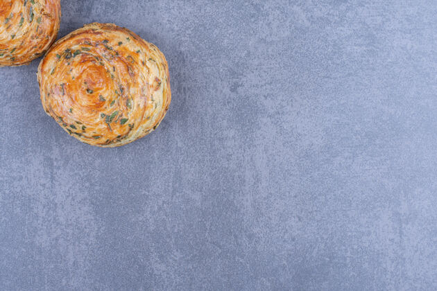 面包房两个新鲜美味的糕点放在灰色的表面上糕点新鲜可食用