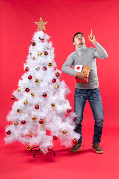 男人迷茫帅哥站在装饰的白色圣诞树旁的垂直视图身材迷茫漂亮