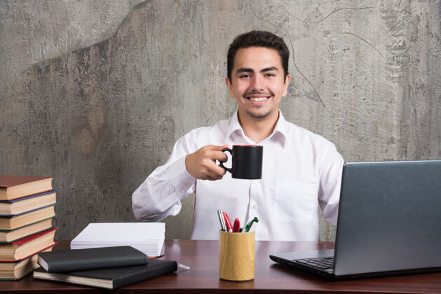 商人商人端着一杯茶微笑着坐在办公桌旁书办公室人