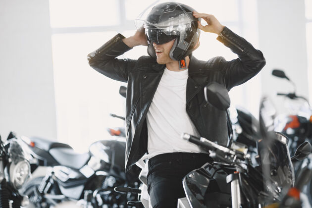 商店一个男人在摩托店里选摩托车一个穿黑夹克的男人一个戴头盔的男人消费主义阳刚男人