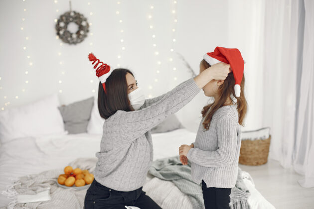 孩子为圣诞节做准备的人冠状病毒主题妈妈和女儿玩穿着灰色毛衣的孩子毛衣黑发小