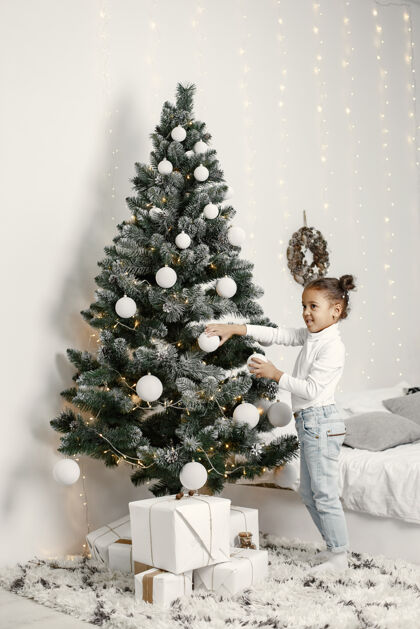 非洲穿白色毛衣的孩子站在圣诞树旁的女儿房间孩子圣诞树